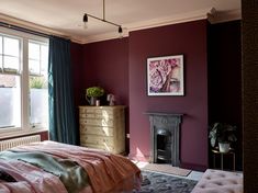 a bedroom with purple walls and a pink blanket on the bed in front of a window