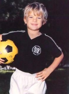 a young boy holding a yellow soccer ball