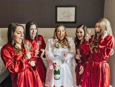 a group of women in red robes standing next to each other holding wine glasses and champagne bottles