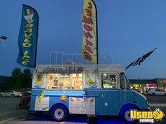 an ice cream truck is parked on the side of the road with flags in front of it