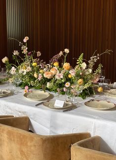 the table is set with plates and flowers in vases on it, along with silverware