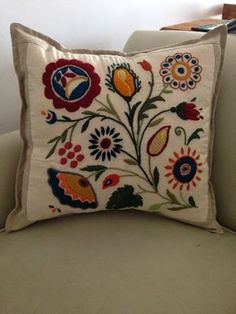 an embroidered pillow is sitting on a couch