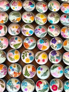 many bowls with flowers painted on them are lined up in the shape of a wall