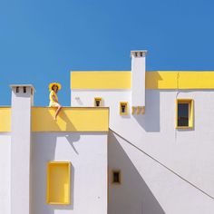 a woman sitting on top of a yellow and white building