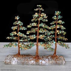 two small trees are made out of wire and glass beaded with green beads on the branches