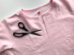 a pair of black scissors laying on top of a pink t - shirt that is cut in half