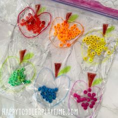 plastic bag filled with beads and hearts shaped like apples on top of a marble table