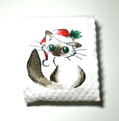 a cat with a santa hat on it's head is sitting in front of a white wall