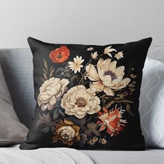 a black background with white and red flowers on it, including an orange flower throw pillow