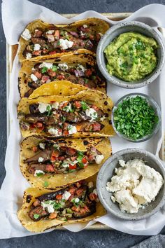 mexican food is laid out on a tray with salsa and guacamole in bowls