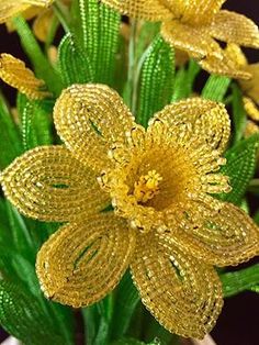 a vase filled with yellow flowers sitting on top of a wooden table covered in sequins