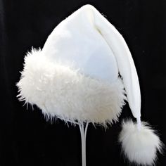 "Novelty Santa hat is made up in a creamy and cozy winter white or ivory tone poly fleece fabric. Hat is styled in the classic Santa slouch cone and is accented with a soft matching faux fur fabric turn up brim with a faux fur pompom on the top. Proportions of the hat are generous and will fit most head sizes, ladies or gents.  Measurement for opening for your head is 24-25\" circumference and the length is 20\". Check measurements to make sure this size will work for you.   Custom orders for si White Christmas Hat, White Winter Hat, One Size Fits Most, White Short Brim Felt Hat For Winter, White Mini Hats For Winter Party, White Brimmed Felt Hat For Party, Adjustable Cream Winter Felt Hat, Adjustable White Felt Hat For Winter, White Wide Brim Mini Hat For Winter, White Beanie Costume Hat For Winter