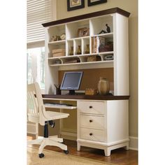 a desk with a computer on top of it in front of a bookcase and window