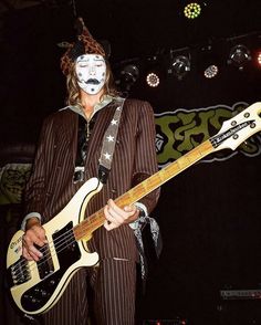 a man in a clown mask playing an electric guitar on stage with his face painted white