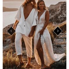 a man and woman standing next to each other in front of the ocean wearing white outfits