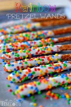 colorful pretzel wands lined up on a baking sheet with sprinkles