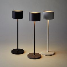 three lamps with black and white shades on each lamp, one is turned off to the side