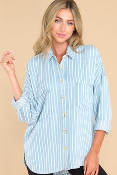 This blue top features a collared neckline, functional buttons down the front, two functional bust pockets, long sleeves with buttoned cuffs, a scoop bottom hem, and a super soft material. Blue Tops With Roll-up Sleeves For Spring, Blue Tops With Roll-up Sleeves For Daywear, Chic Light Wash Button-up Tops, Chic Light Wash Top With Button Closure, Light Wash Button Top For Day Out, Light Wash Buttoned Tops For Day Out, Blue Collared Top With Roll-up Sleeves, Oversized Light Blue Collared Top, Oversized Collared Light Blue Top