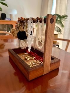 a wooden table topped with lots of necklaces and rings in a display case on top of it