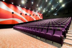 an empty auditorium with purple chairs and bright lights on the ceiling, in front of a large american flag wall