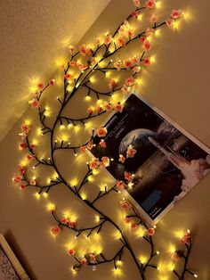 a tree with some lights on it in front of a photo and an image hanging on the wall