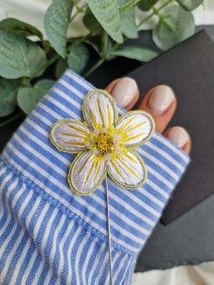 a hand holding a pin with a flower on it