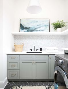 a washer and dryer in a small room with white walls, gray cabinets and black flooring