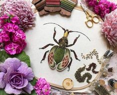 a close up of a embroidery on a table with flowers and crafting supplies around it