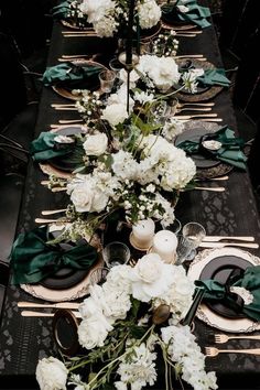 a long table is set with white flowers and green napkins for an elegant dinner