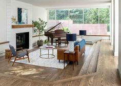 a living room filled with furniture and a piano on top of a hard wood floor