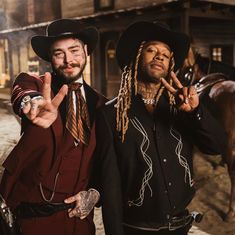 two men dressed in western style clothing standing next to each other and making the peace sign