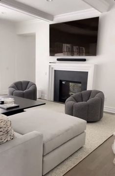 a living room with couches, chairs and a television mounted above the fire place