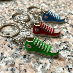 three pairs of shoes key chains sitting on top of a marble counter with one shoe painted red, the other green