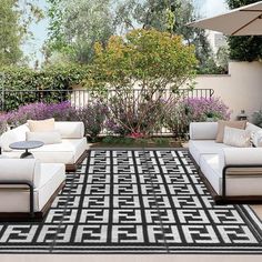 an outdoor living room with white furniture and black and white rugs on the floor