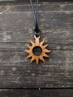 a wooden sun pendant hanging on a black cord