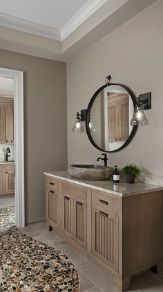 a bathroom with a round mirror above the sink and two lights on the wall next to it