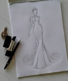 a drawing of a woman in a dress on paper next to a pen and ink