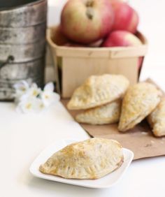 apple turnovers are on a plate next to some flowers and an old tin can