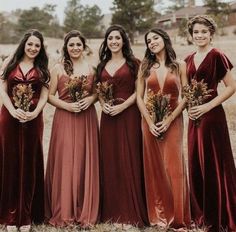 a group of women standing next to each other in long dresses with flowers on them