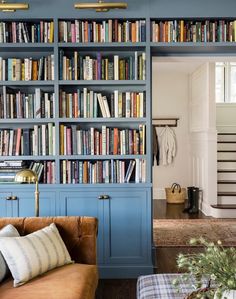 a living room filled with lots of books on top of a blue book shelf next to a couch