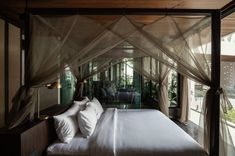 a bed with white sheets and pillows in a bedroom next to a large glass window