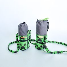 two green and black bags sitting next to each other on top of a white surface