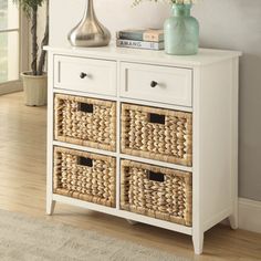 a white dresser with wicker baskets on top and a vase filled with flowers next to it