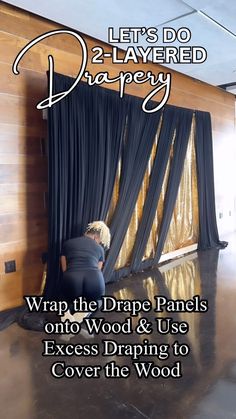 a person sitting on the floor in front of a black curtain with gold foil covering it