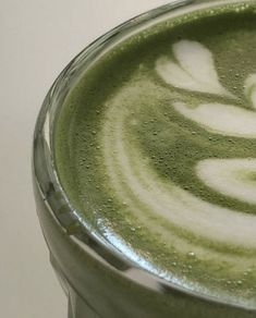 a glass filled with green liquid on top of a table