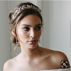 a woman wearing a bridal headpiece with gold leaves on it's hair