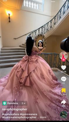 a woman in a pink dress is taking a selfie with her cell phone while standing on the stairs