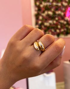 a woman's hand holding a gold ring with two rings on top of it