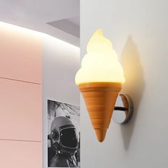 an ice cream cone shaped light fixture on the wall next to a pink and white room