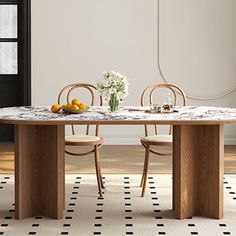 a dining room table with chairs and fruit on the table in front of an open door